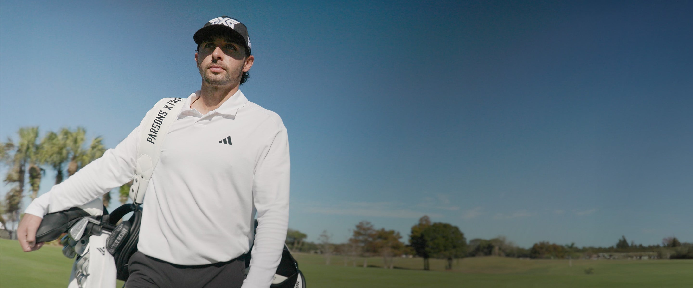 Marco Penge on a golf course wearing a pxg black hat.