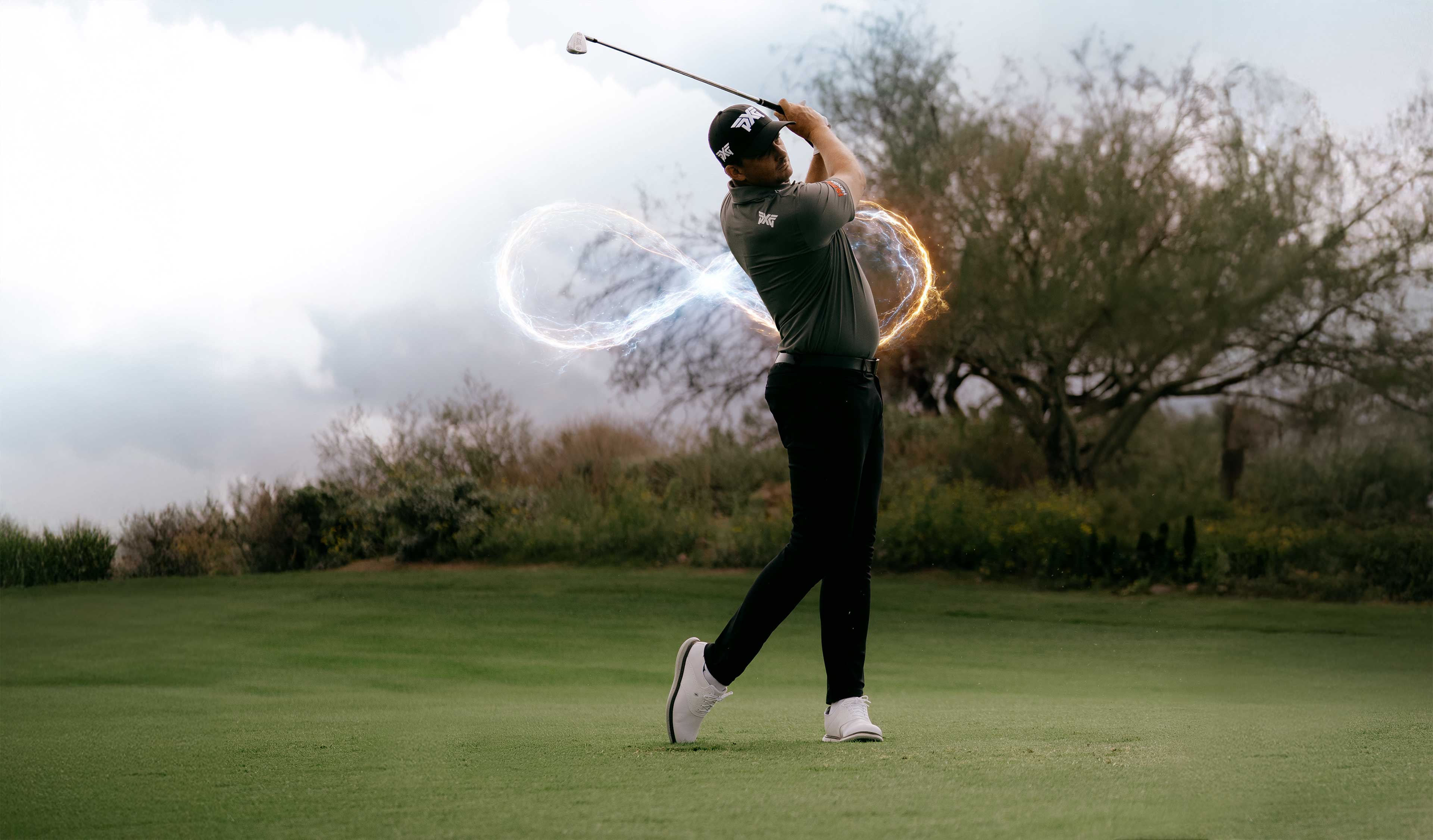 Golfer swinging a club on a golf course with trees and sky in the background