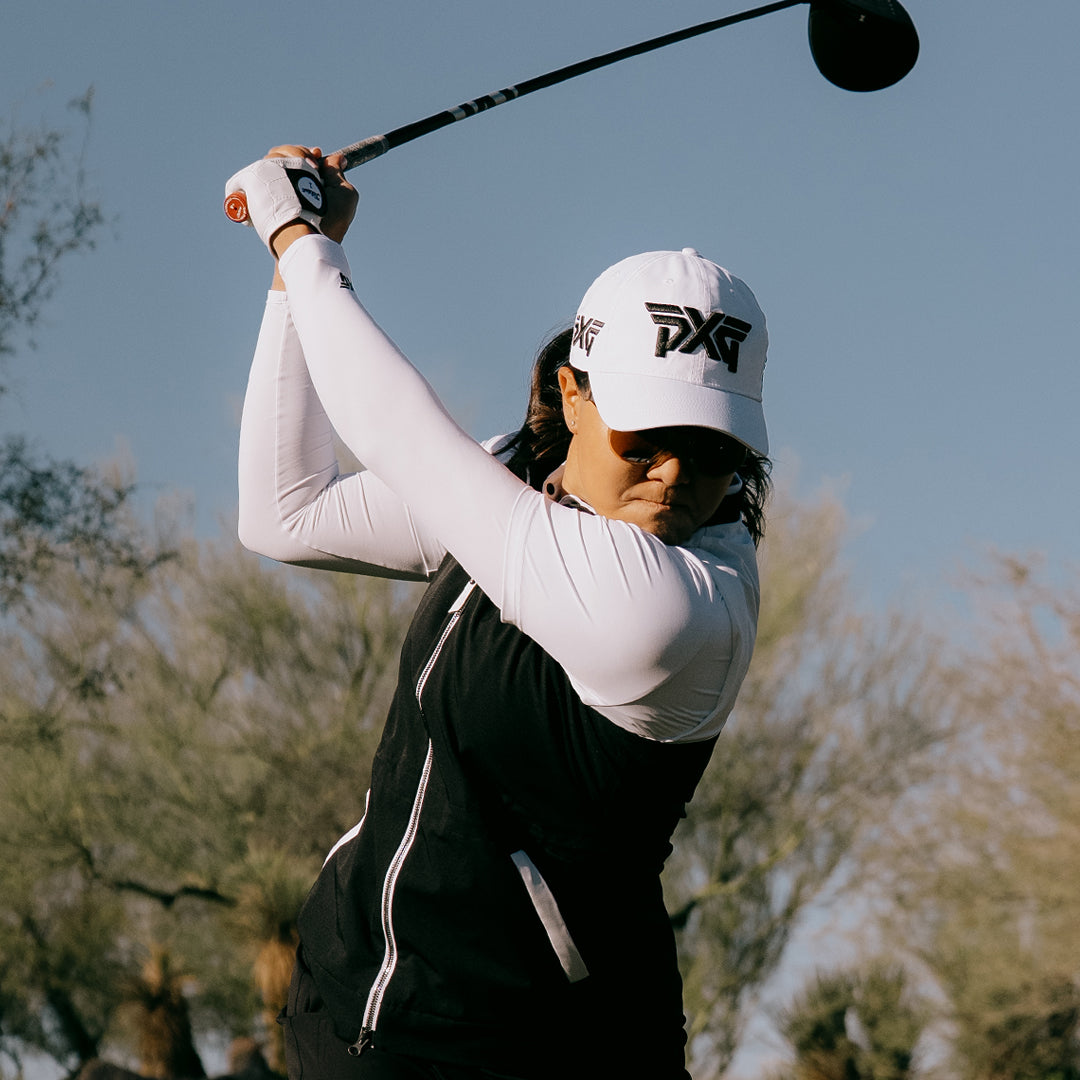 LPGA Tour Pro Auston Kim wearing a PXG Golf Hat swinging a golf club on a golf course.