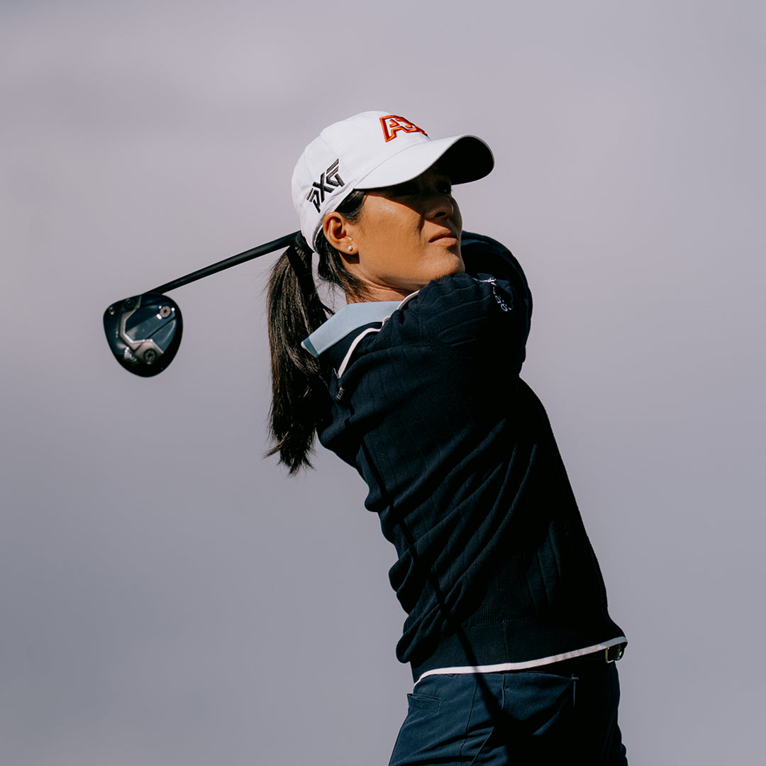 LPGA Tour Pro Celine Boutier wearing a PXG Golf Hat against a gray sky.
