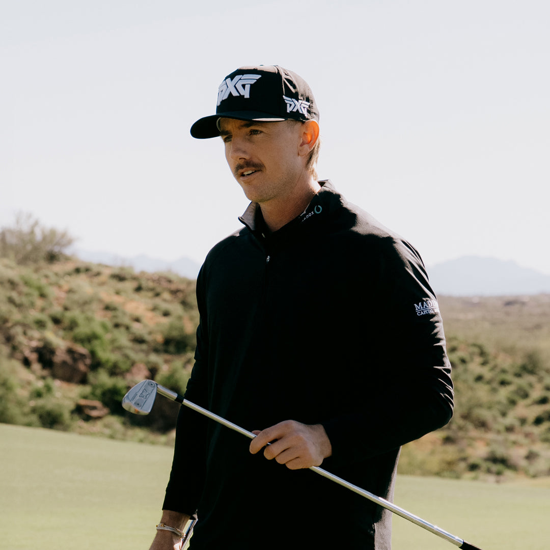 PGA Tour Pro Jake Knapp wearing a PXG Golf Hat on a golf course holding a golf club.