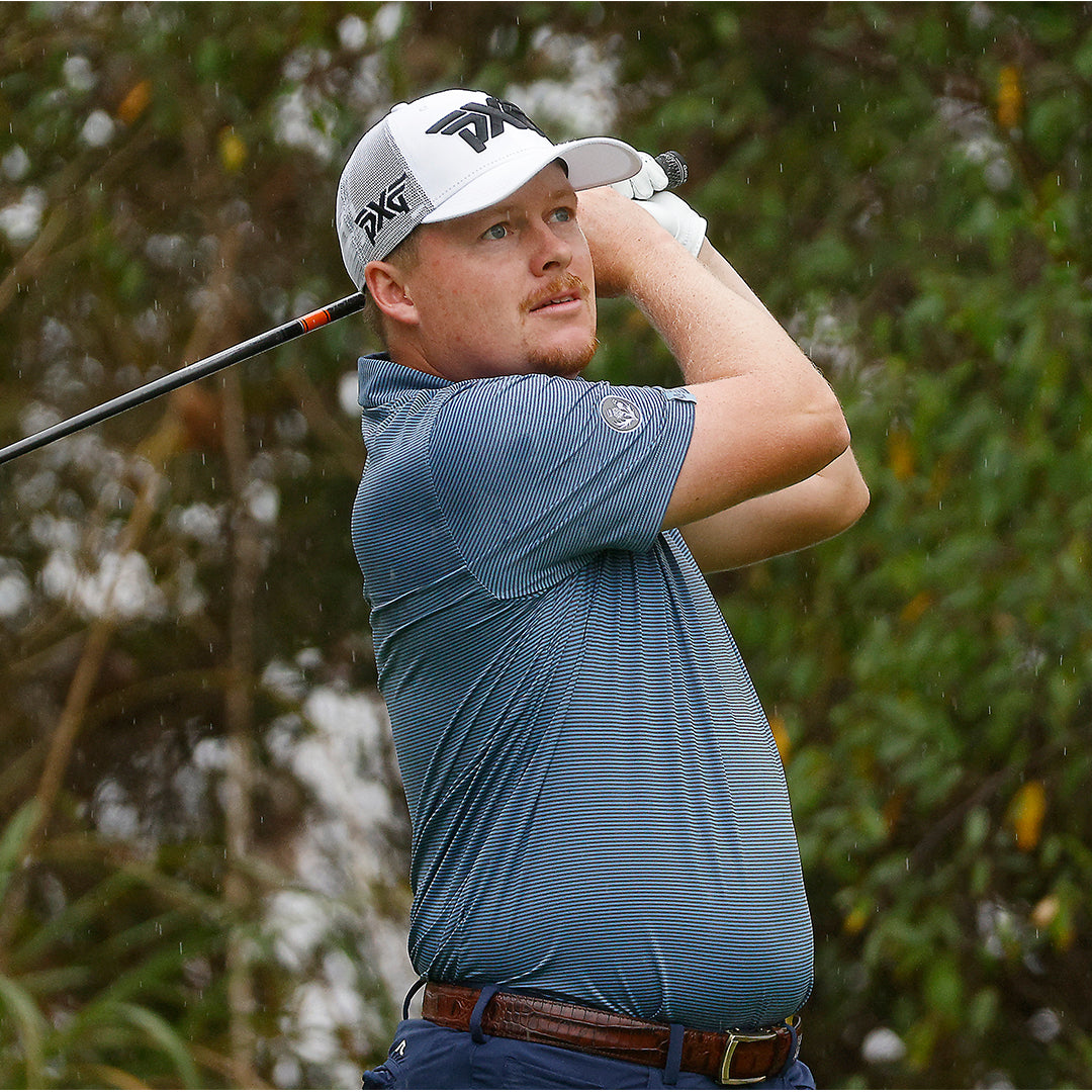 Pro Shad Tuten wearing a PXG Hat and swinging a golf club on a golf course.