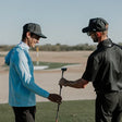 Two men on a golf course with one holding a golf club